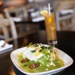 Avocado, plantains & rice burrito in cilantro-parsley sauce, topped with fried eggs, served with a Tamarind Margarita